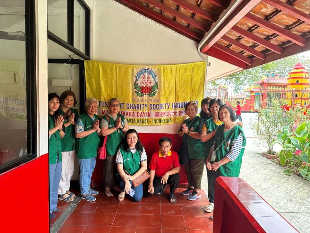 Kelompok sukarelawan Lotus Light Charity Society Indonesia bersama di depan banner.