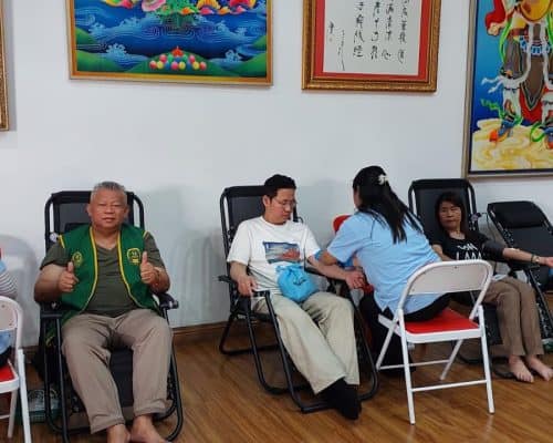 Relawan dan peserta kegiatan sosial di ruang berdekorasi seni Buddha dan Pancasila.