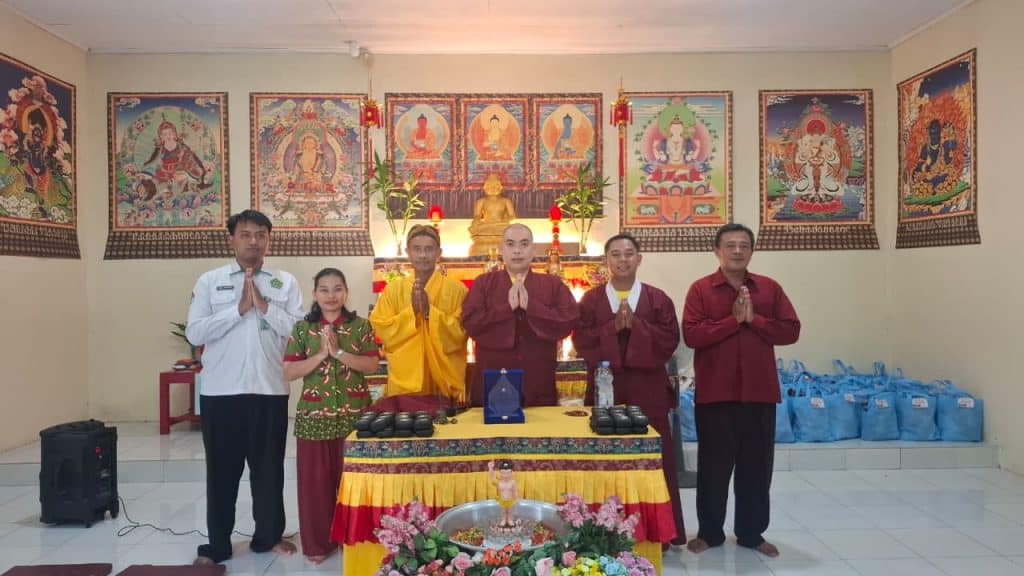 Kelima orang berdiri di depan altar Buddha saat acara Waisak di Indonesia.