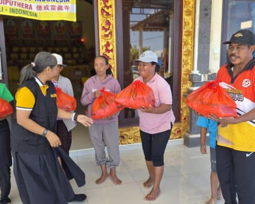 Relawan membagikan paket sembako kepada warga di Bali.