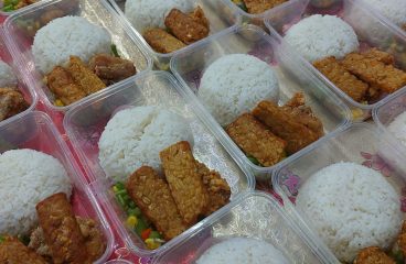 Porsi nasi dan lauk dalam kemasan plastik untuk berbagi makanan.