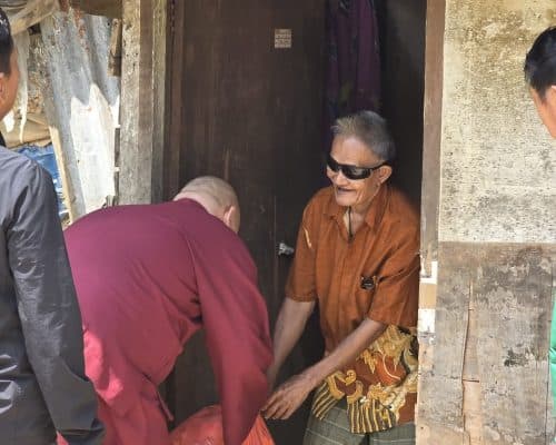 Relawan memberikan bantuan kepada warga di depan rumah sederhana di Indonesia.