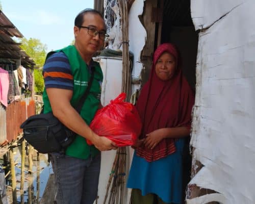 Relawan Lotus Light Charity Society Indonesia menyerahkan bantuan kepada warga miskin.