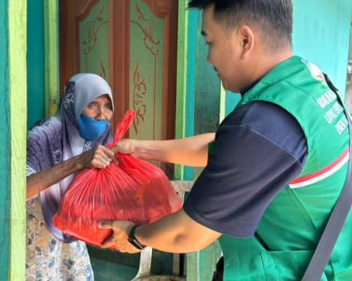 Relawan Lotus Light Charity Society Indonesia menyerahkan bantuan kepada warga.